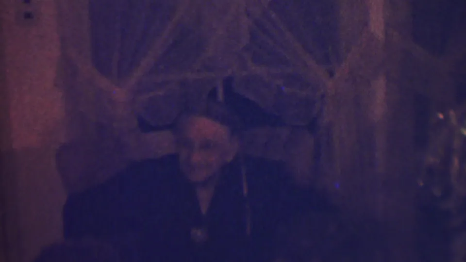 At the end of the short clip, the older woman sits in shadow near holiday decorations and a Christmas tree in the private Terre Haute interior.