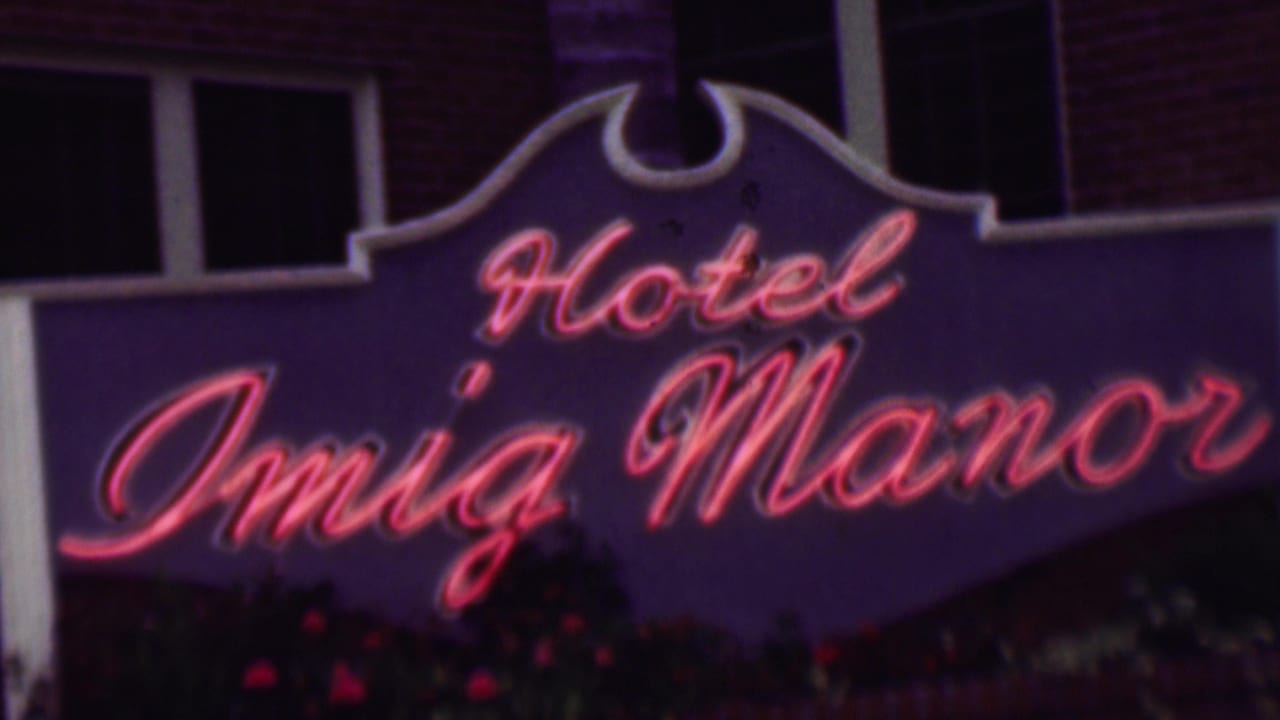 Close view of the Hotel Imig Manor sign with glowing red script.