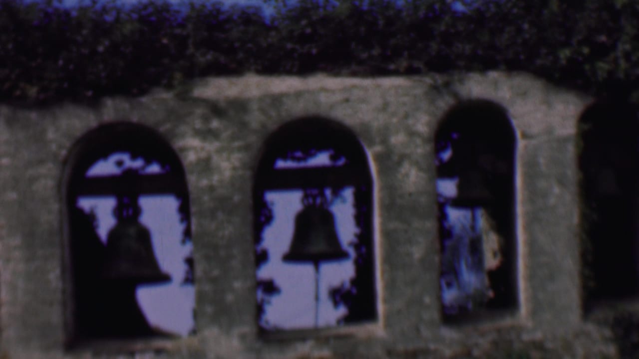Multiple arched openings in a stone bell tower with bells visible in shadow.