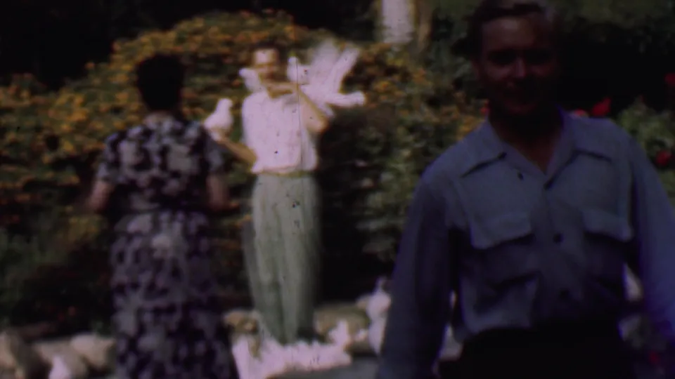 The final 1961 San Diego frame places a man close to the camera in shadow while, behind him, another man holds white pigeons in a lush garden with shrubs and rocks.