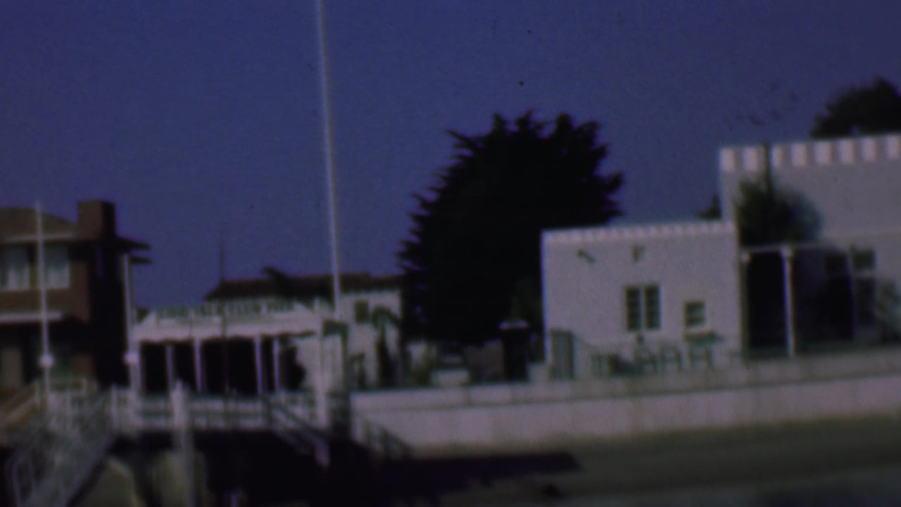 White building complex beside a pier-like structure and flagpole.