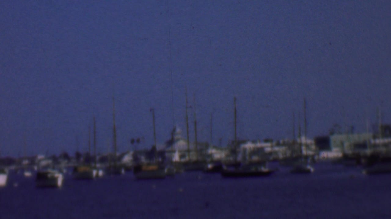 A harbor channel with boats and tall masts stretches across the frame.