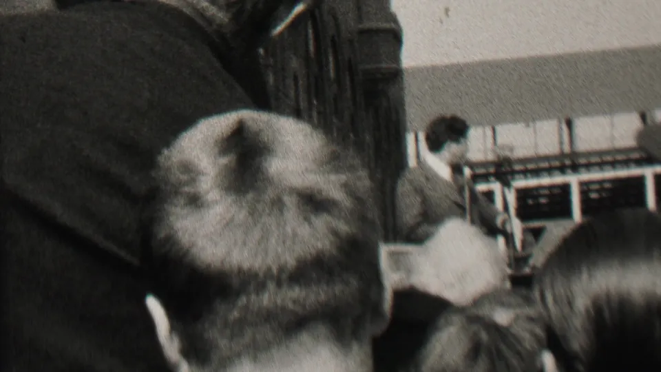 Albany, New York 1937 8mm frame showing audience members seen from behind while a suited man appears to address the room from the front.