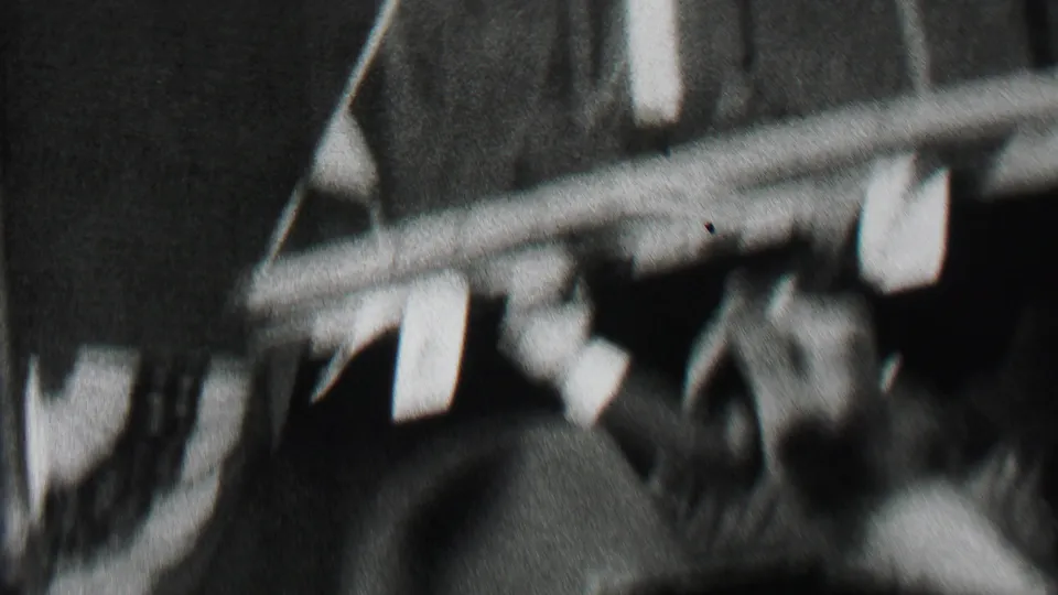 A blurred handheld view from the 1937 Albany procession shows the car and crowd moving past the camera beneath awnings and brick building details.
