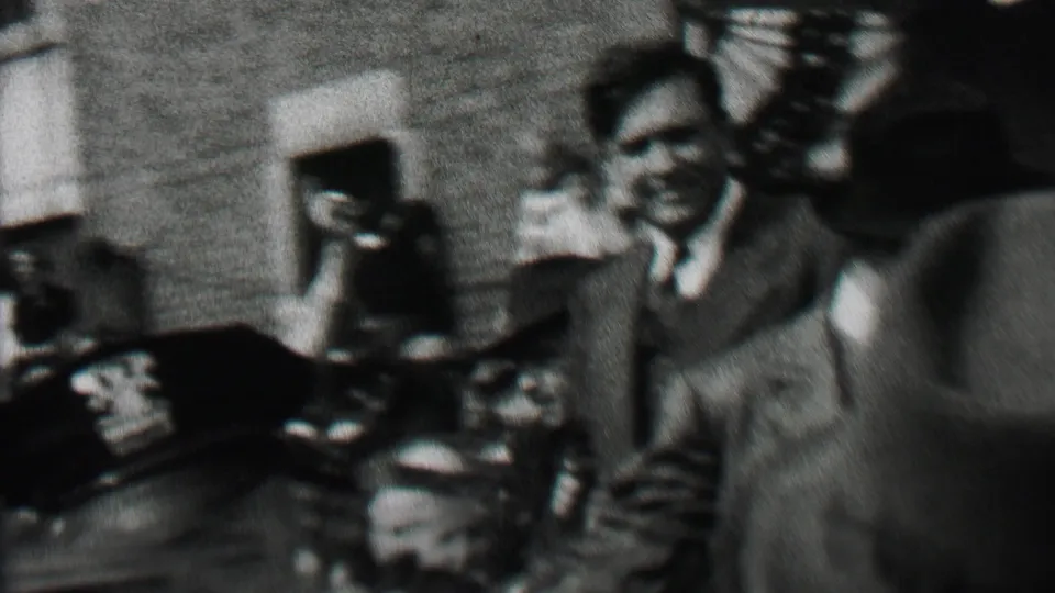 Near the end of the Albany 1937 clip, the suited campaign figure waves from the car as men in hats and onlookers fill the foreground and background.