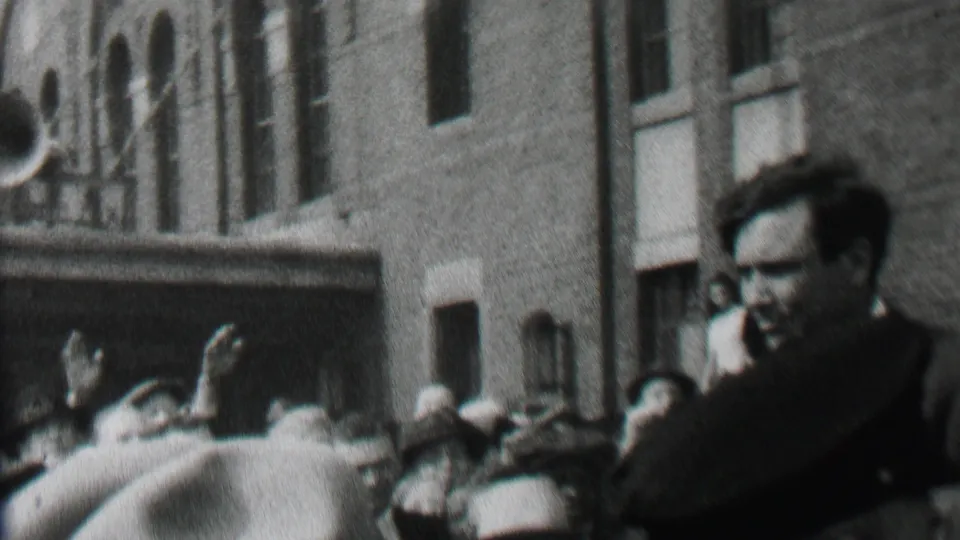 The 1937 Albany crowd scene shows the suited man partly obscured by raised hands and spectators, with uniformed police and a brick building behind him.