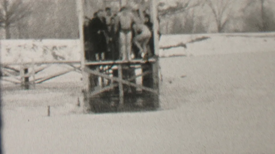 In the Albany winter scene, one person appears to dive headfirst from the wooden platform while bundled onlookers stand nearby against a snowy shoreline.