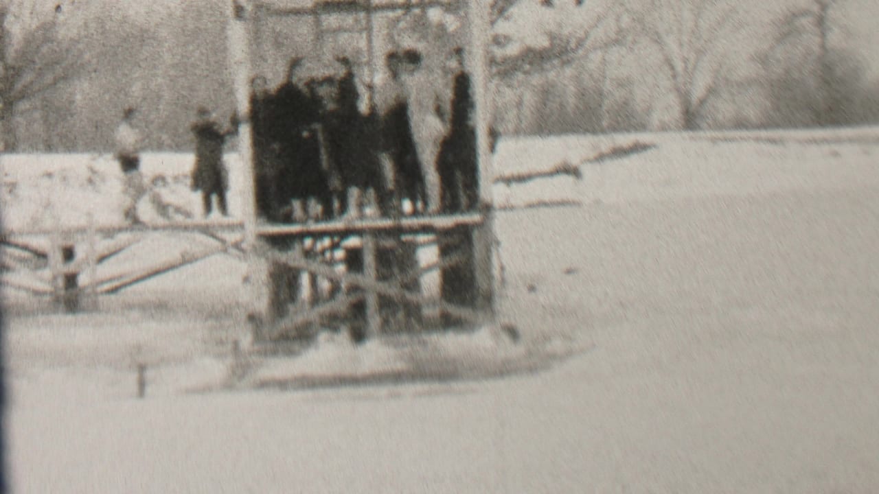People cluster near the edge of a wooden platform above snow and icy water.