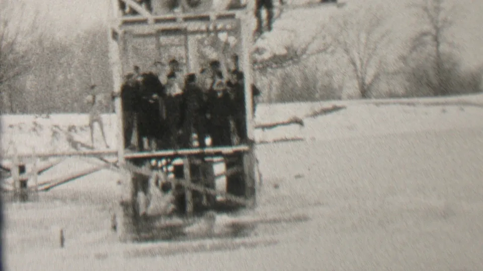 The final frame shows bundled spectators grouped on a wooden platform over dark water, with snow and bare trees reinforcing the 1937 Albany winter setting.