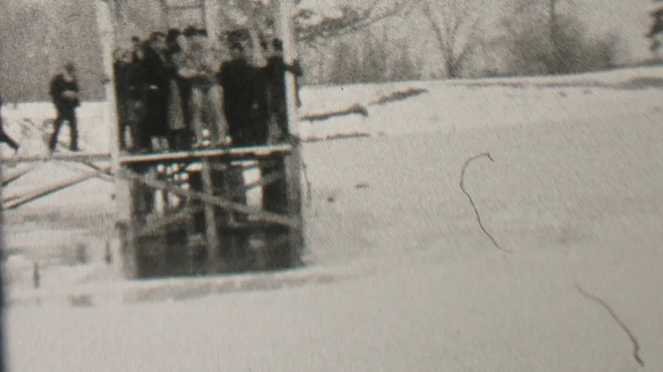 Albany, New York 1937 frame showing a winter lakeside platform crowded with men in coats, with snow, bare trees, and a nearby walking figure visible.