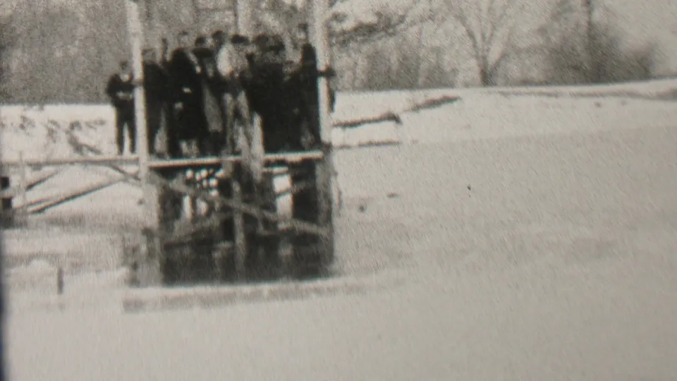 In this 1937 Albany home-movie frame, the crowd remains on the dock while one figure appears lower at the edge, near the water below the platform.