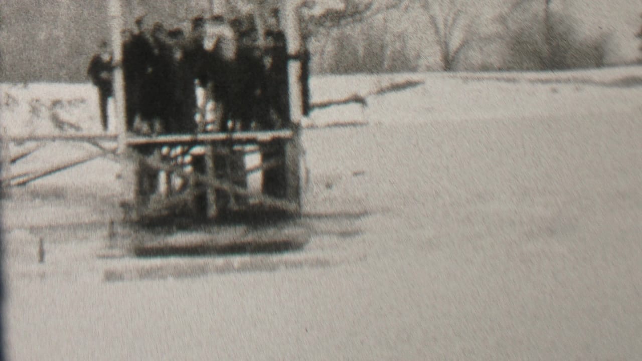 In Albany, New York 1937 home-movie footage, spectators in winter coats gather near a wooden diving platform beside snow-covered water.