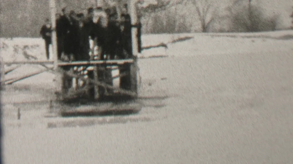 In Albany, New York 1937 home-movie footage, spectators in winter coats gather near a wooden diving platform beside snow-covered water.