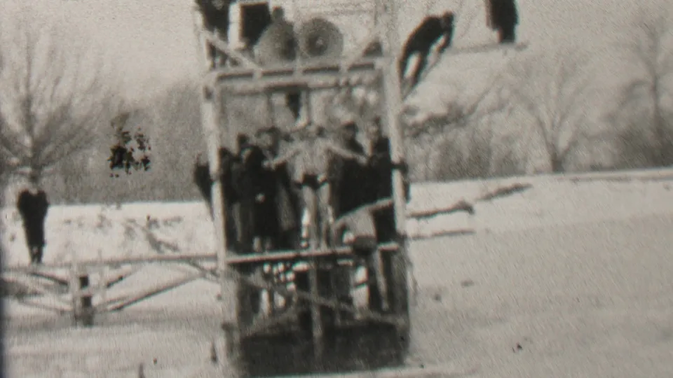 The diver appears positioned on the wooden platform while spectators watch from the snowy shore and structure in the 1937 Albany winter scene.