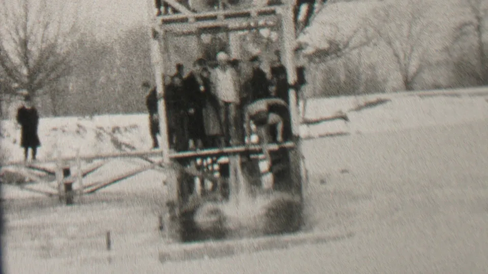 After the icy jump, a splash or disturbed water appears beside the wooden platform as winter-clad onlookers watch in Albany, New York 1937 footage.
