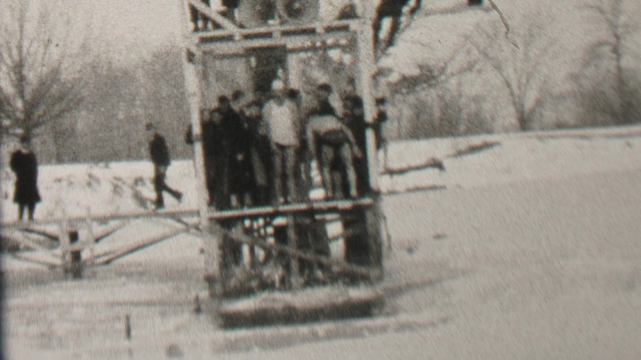 In 1937 Albany, New York, bundled spectators gather around a wooden platform on a frozen or icy body of water, with snow and bare trees in the background.