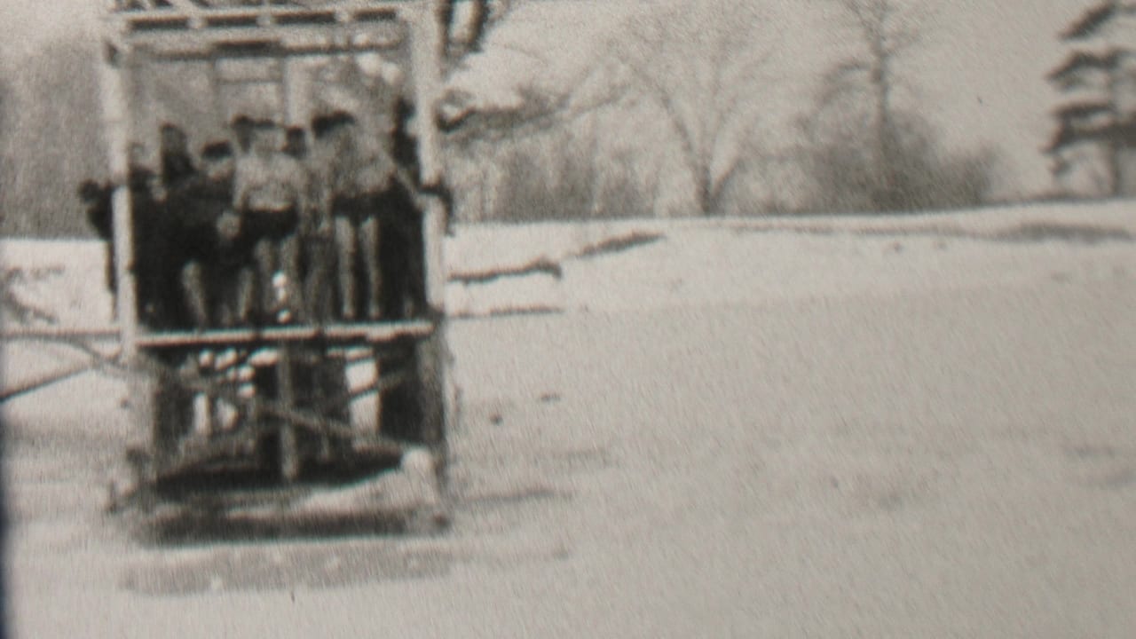 In stated 1937 Albany-area 8mm footage, a group of young men in dark swimwear stands within a wooden lake structure against bare winter trees.