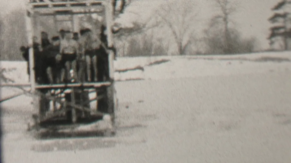 In stated 1937 Albany-area 8mm footage, a group of young men in dark swimwear stands within a wooden lake structure against bare winter trees.