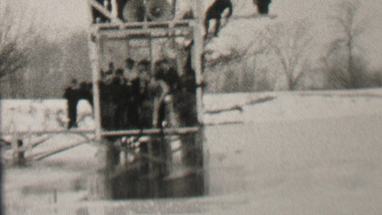 Group of young men cluster on a wooden platform over a frozen lake.