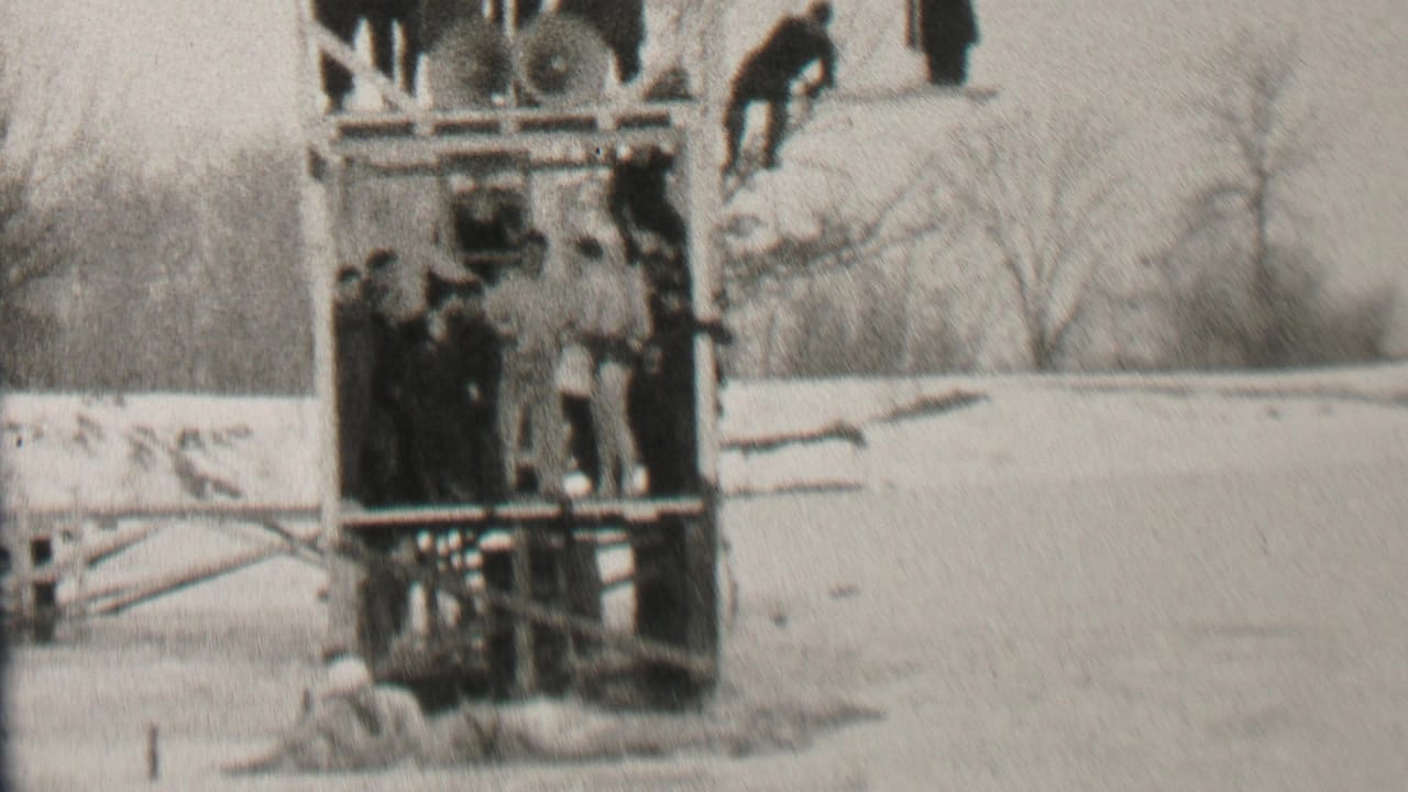 In the stated 1937 Albany, New York context, spectators in winter clothing gather on and around a wooden platform beside snow-covered ground and bare trees.