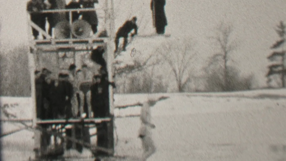 The final frame shows the wooden platform with spectators and a foreground figure in winter clothing, maintaining the cold outdoor recreation context from the Albany clip metadata.