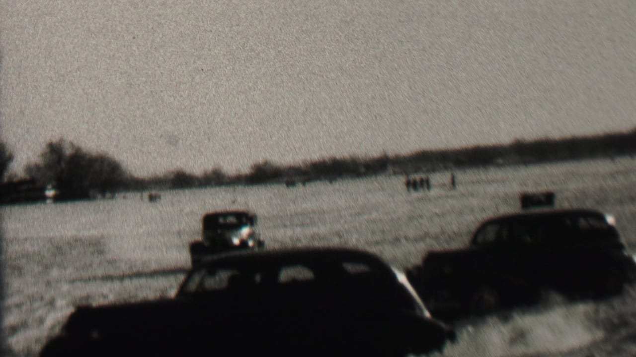 Several dark cars spread across a snowy field.
