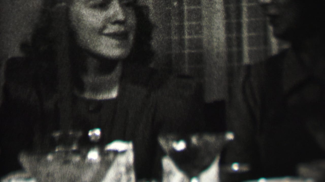 A smiling woman sits at a candlelit dining table in Albany, New York, with partially visible adult companions and table glassware around her.