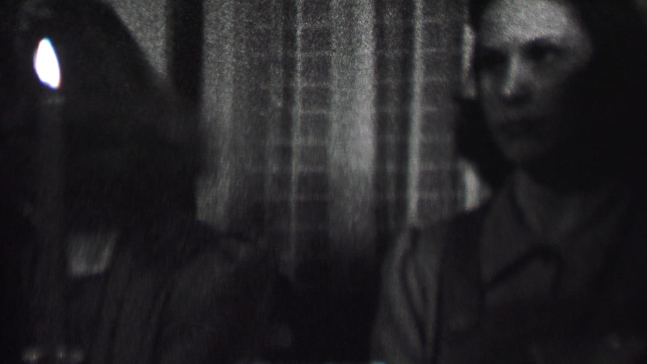 Albany, New York home-movie frame from 1937 showing women seated close together in a dark interior with a candle at the edge of the frame.