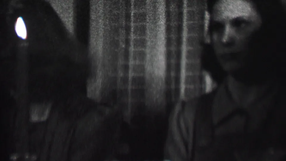 Albany, New York home-movie frame from 1937 showing women seated close together in a dark interior with a candle at the edge of the frame.