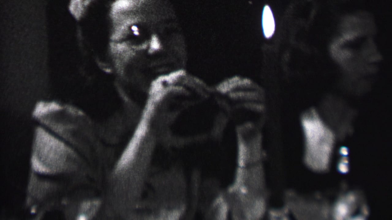 Woman smiling while holding something near her mouth beside a lit candle.