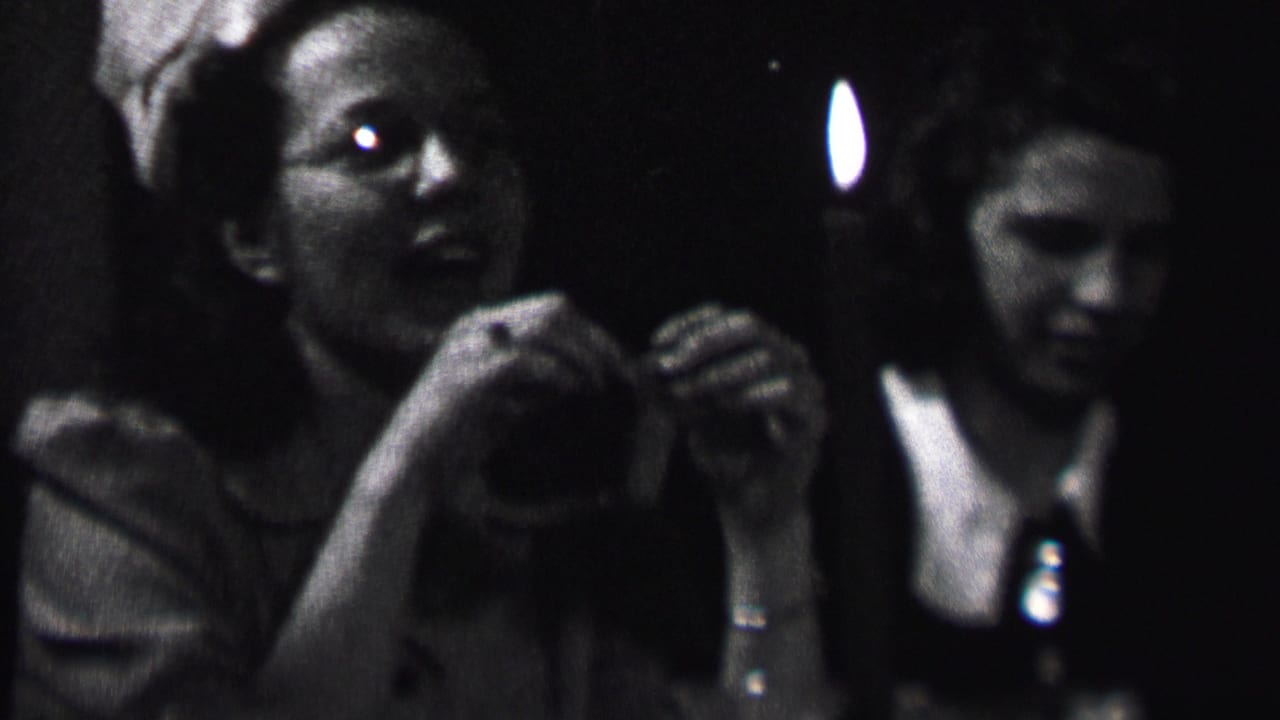 Black-and-white 8mm frame from Albany, 1937, with a young woman near the candle and another woman in a white-collared dress behind her.