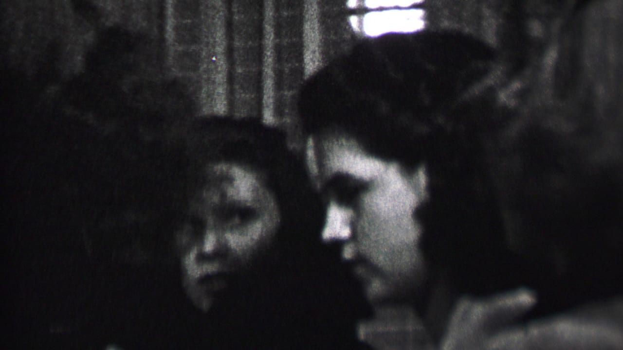 Two young women in profile and partial front view inside a dark room.