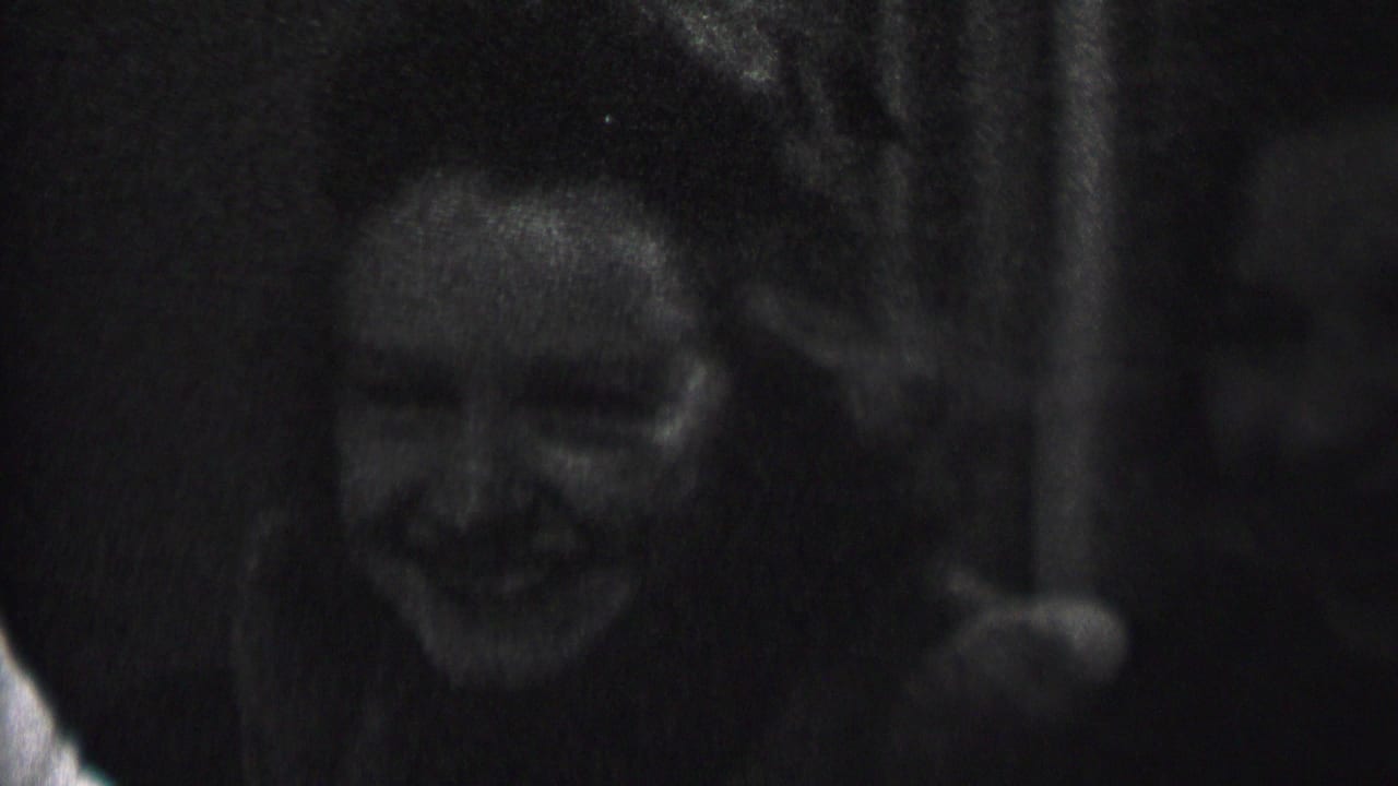 In this 1937 Albany home-movie frame, two young women appear to laugh together in a dark indoor space, with soft focus and strong film grain.