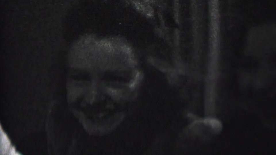 In this 1937 Albany home-movie frame, two young women appear to laugh together in a dark indoor space, with soft focus and strong film grain.