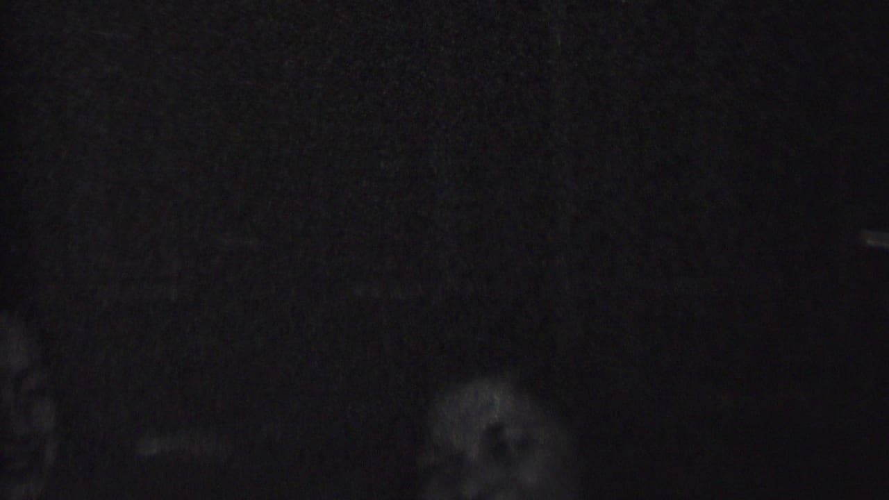Very dim 1937 Albany home-movie frame with partial faces or silhouettes barely visible against a dark background.