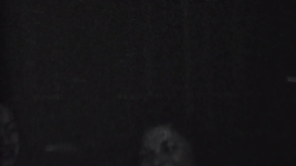 Very dim 1937 Albany home-movie frame with partial faces or silhouettes barely visible against a dark background.