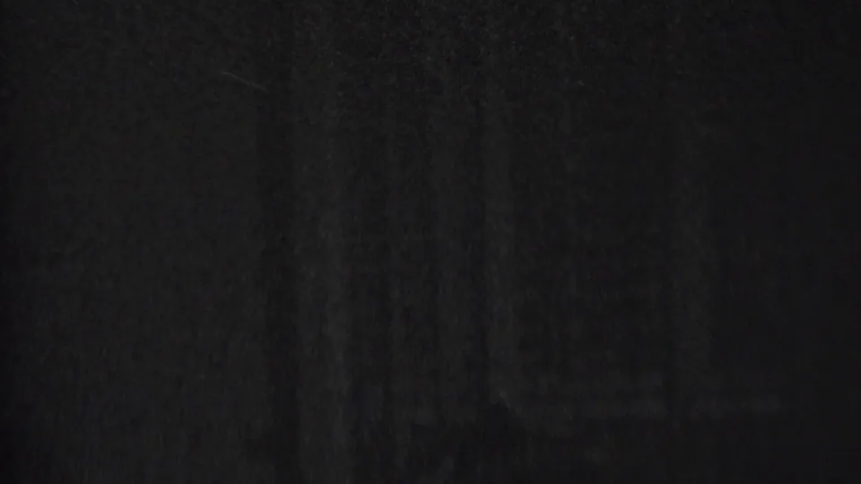 Final sampled frame from the 1937 Albany 8mm clip, showing a barely readable human outline in very dim light with heavy grain and soft exposure.