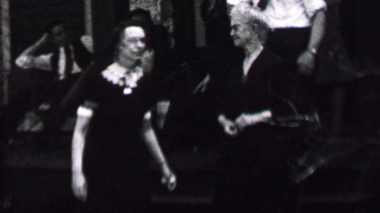 Albany, New York, 1937 home-movie frame showing adults gathered in soft focus, with a woman in a dark dress and light collar most visible at left.