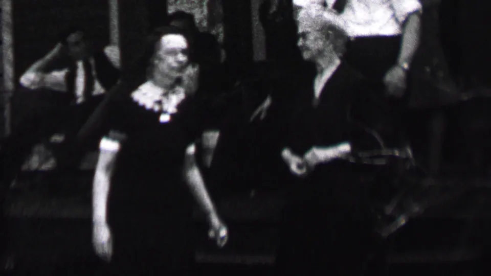 Albany, New York, 1937 home-movie frame showing adults gathered in soft focus, with a woman in a dark dress and light collar most visible at left.
