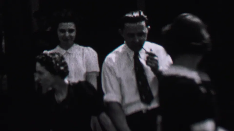 Albany, New York, 1937 home-movie frame with a smiling woman in a light blouse near a man in a white shirt and tie holding a pipe.