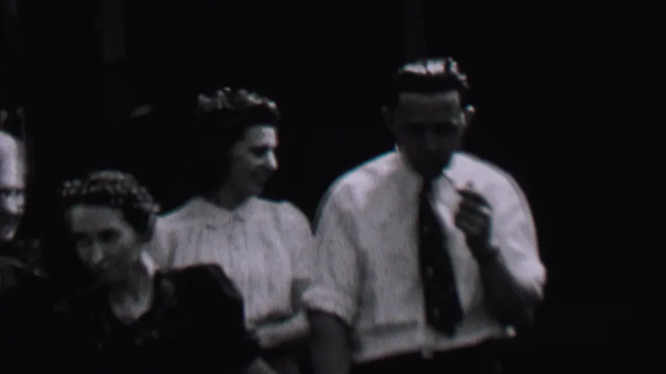 Albany, New York, 1937 frame showing several women grouped in dim light while a pipe-smoking man in a white shirt and tie stands at right.