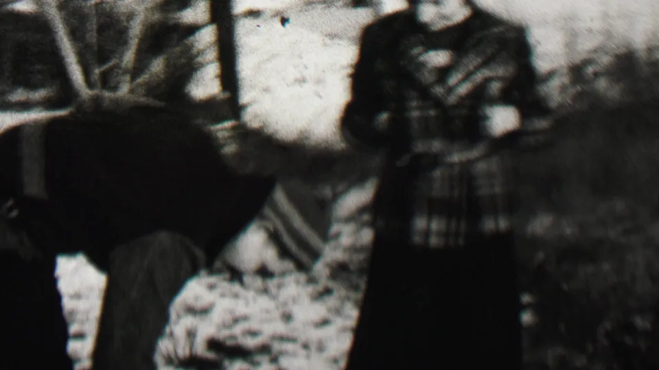 A dark-clothed person bends close to the snowy ground while a woman in a plaid winter coat stands nearby in the 1937 Beachwood, New Jersey outdoor scene.