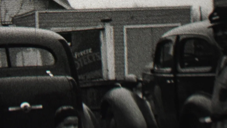 In the supplied 1937 Beachwood, New Jersey home-movie context, parked 1930s cars sit in front of a suburban house and garage while a man in a cap is partly visible.