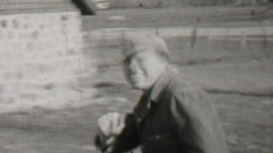 Black-and-white 1937 Beachwood, New Jersey home-movie frame showing an adult man in a cap beside a horse, with wooden fencing and a rural yard behind him.