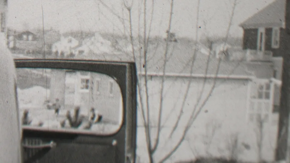 The final frame holds on the open automobile door and window, showing Beachwood residential houses and leafless trees through the soft black-and-white 8mm image.