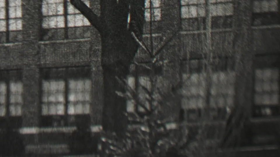 1937 Beachwood, New Jersey frame showing the upper facade of an institutional-looking masonry building with repeated multi-pane windows and leafless branches.