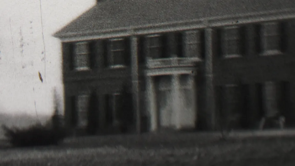 Black-and-white 1937 Beachwood, New Jersey frame showing a large brick house with a columned doorway, symmetrical windows, a front lawn, and a sidewalk in soft 8mm focus.