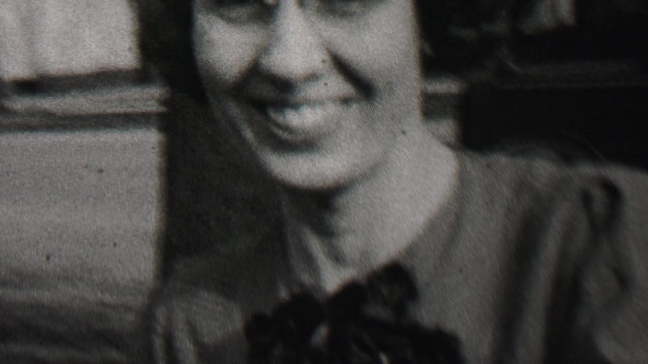 Smiling woman in soft-focus black-and-white home movie frame.