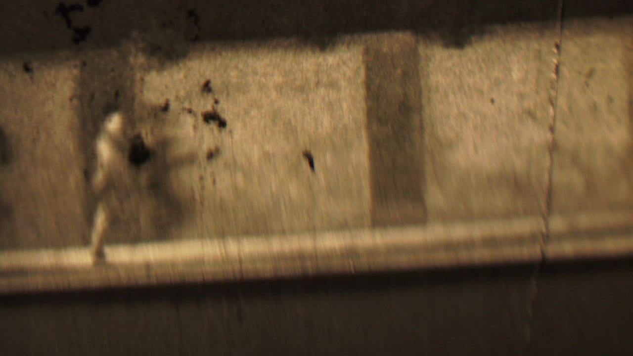 In this 1937 Beachwood, New Jersey 8mm frame, a small blurred running figure crosses a bright, textured surface beneath dark shadow bands.