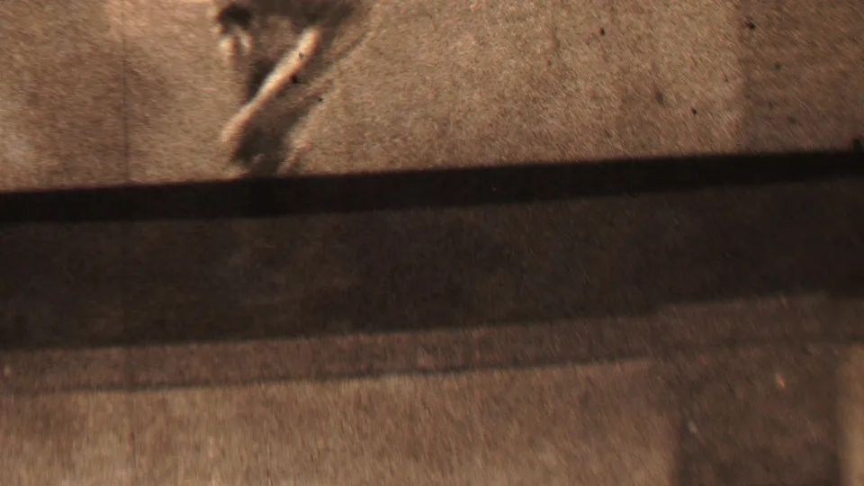 In this 1937 Beachwood, New Jersey 8mm frame, the lower body of a blurred running figure crosses a pale surface above a dark horizontal shadow.